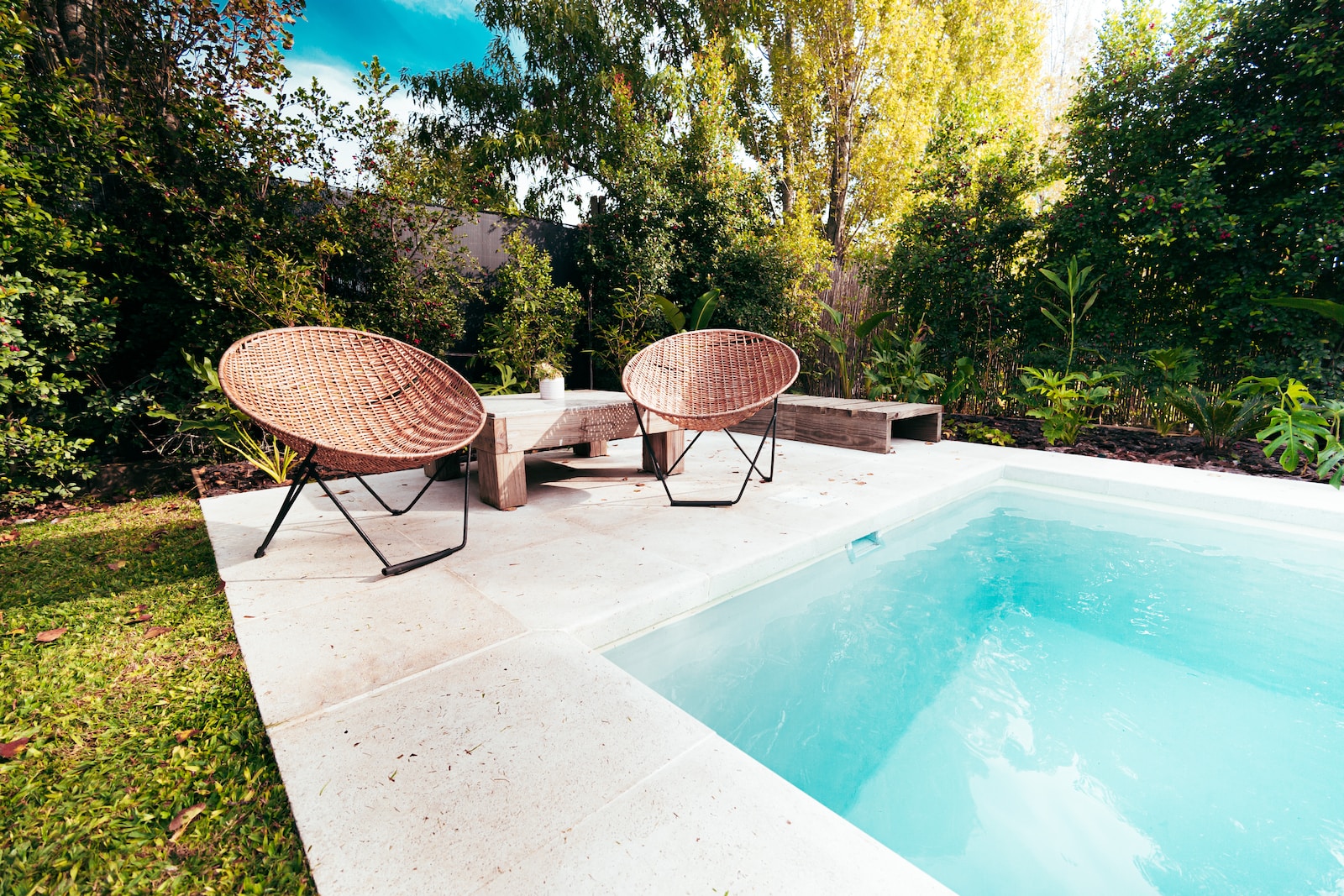two wicker chairs sitting next to a swimming pool